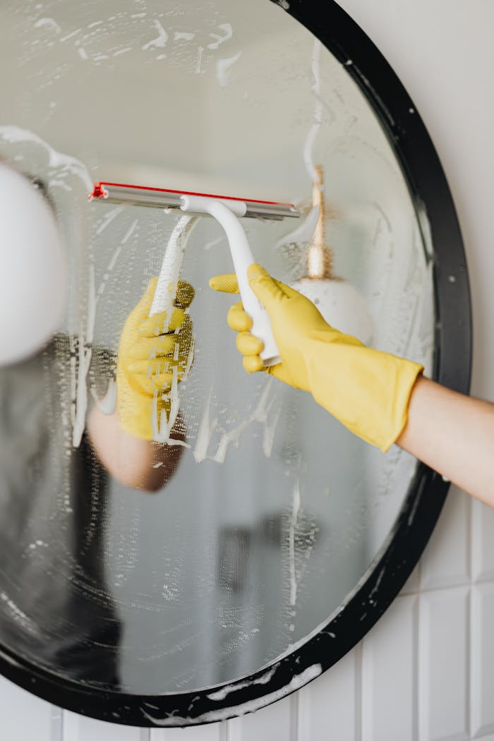 The Art of Drawing Readers In: Your attractive post title goes here Person cleaning a bathroom mirror using a squeegee for shiny, clear results.